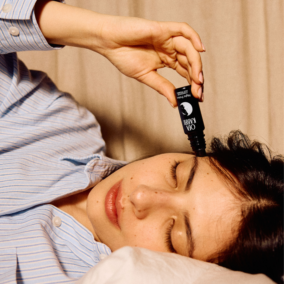 Vrouw in bed brengt de Night Potion roll-on van Ofa Karri aan op haar slaap