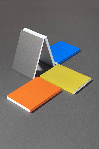 Naked-notitieboeken van mishmash in verschillende kleuren rechtop op een grijze ondergrond