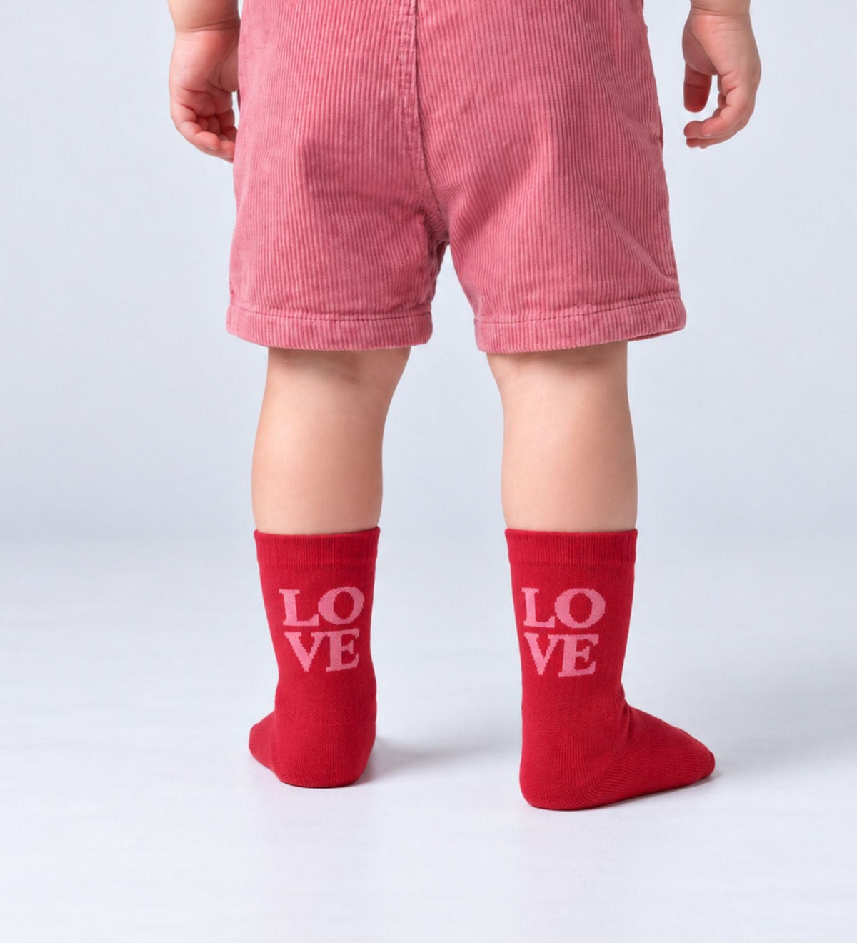 Peuter met rode babysokken Love van No Bad Days Club met roze opschrift 'LOVE'