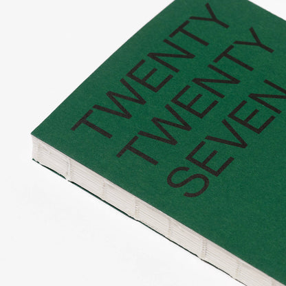 Close-up van het smaragdgroene omslag van de agenda 2027 van This Might Work